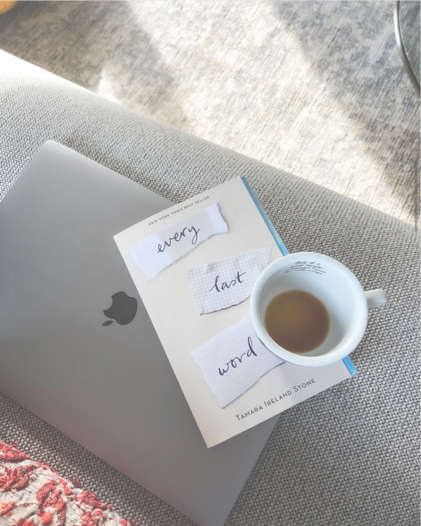 Coffee cup placed on a notebook next to a white sheet of paper with the words 'every last word'